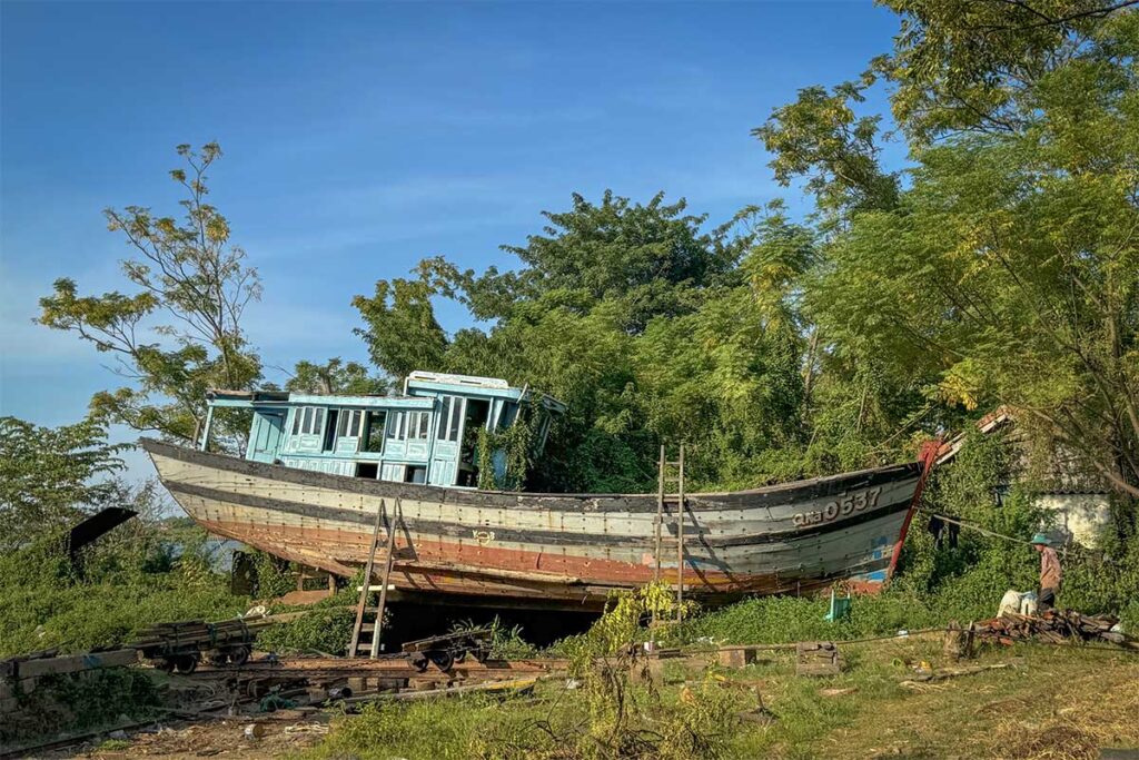 Carpenter working on a wooden boat in Kim Bong Carpentry Village – one of the traditional craft villages around Hoi An known for its skilled artisans.