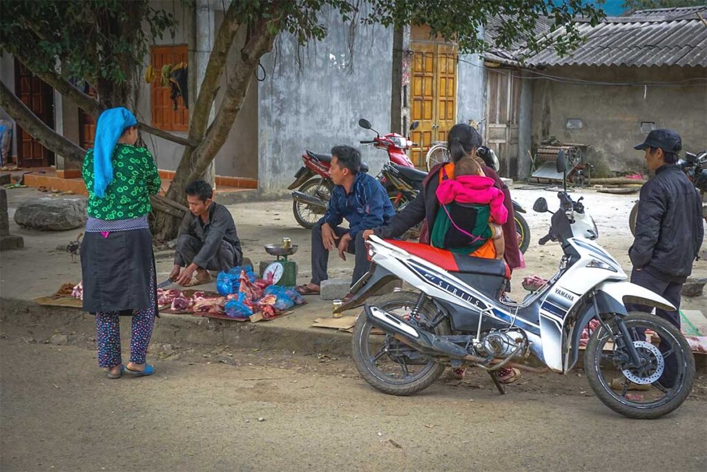 Locals and a motorbike standing in the village of Lung Tam 