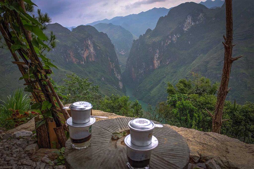 Drinking Vietnamese coffee at a viewpoint on the Ma Pi Leng Pass with views over Nho Que River and the Tu San Canyon