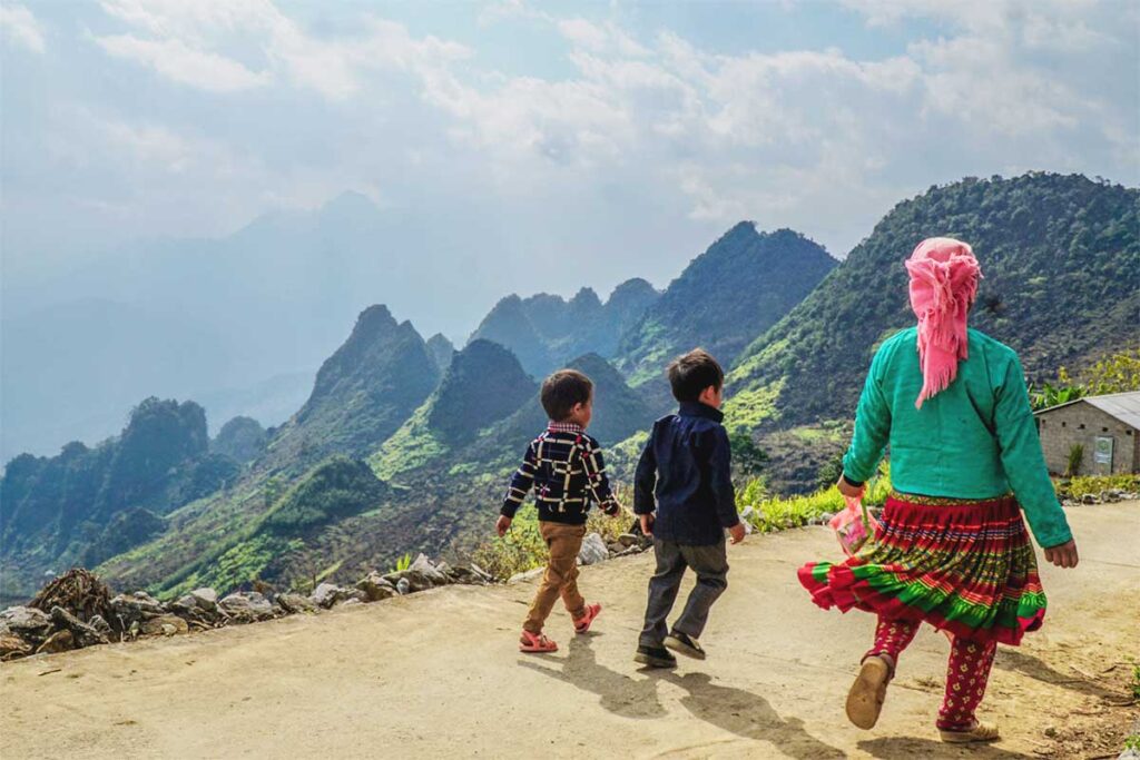 Ethnic minority woman and two children walking down a small mountain road in Meo Vac district, Ha Giang