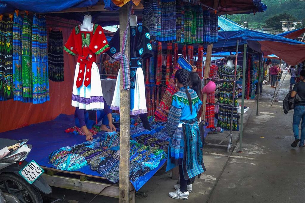 A local girl dressed in traditional ethnic clothes is browsing at an clothes stall on the Muong Khuong Market