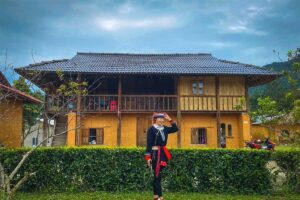 An ethnic Red Dao woman standing in front of a homestay at Nam Dam Village
