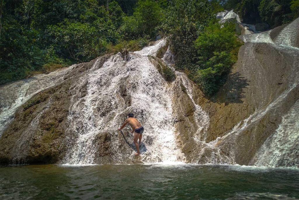 A man climbing up Nam Tau Waterfall in Ha Giang