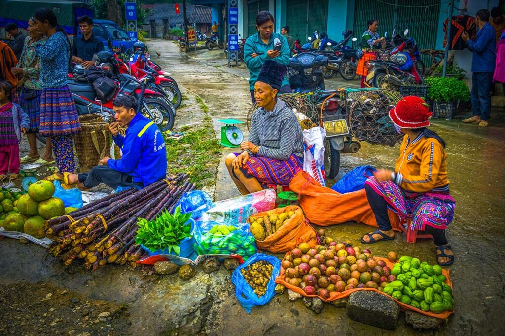 Ethnic woman sitting on the floor at Pa Co Market selling local produce