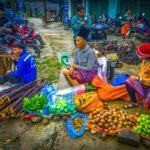 Ethnic woman sitting on the floor at Pa Co Market selling local produce