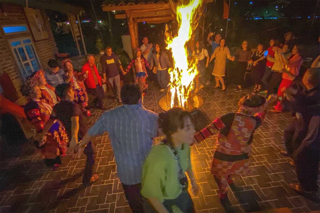 People dance around a campfire at a homestay in  Pa Vi Village