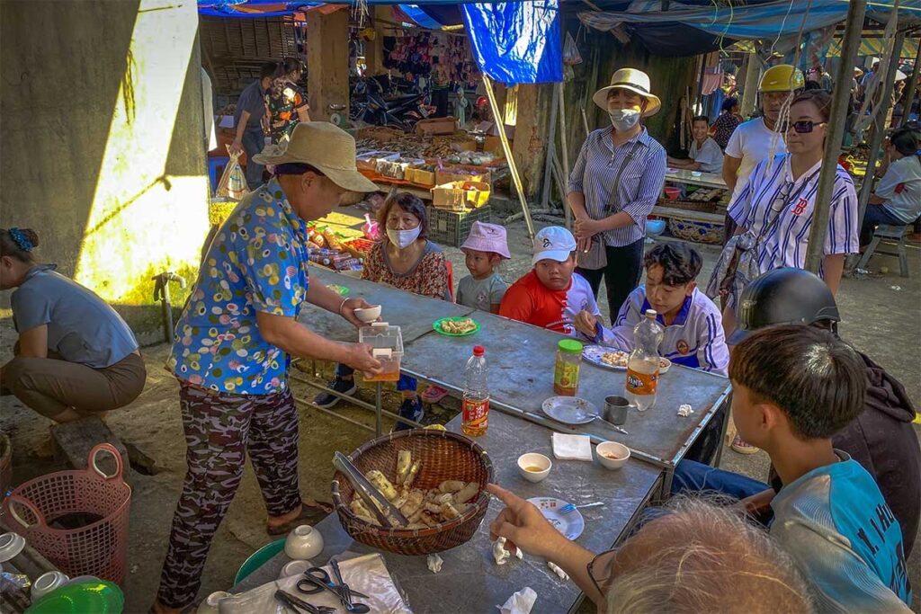 Locals sitting around a table with snacks and drinks at the Pho Doan Market in Phu Luong
