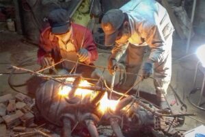 Artisans welding a large bronze sculpture at night in Phuoc Kieu Bronze Casting Village, Vietnam.