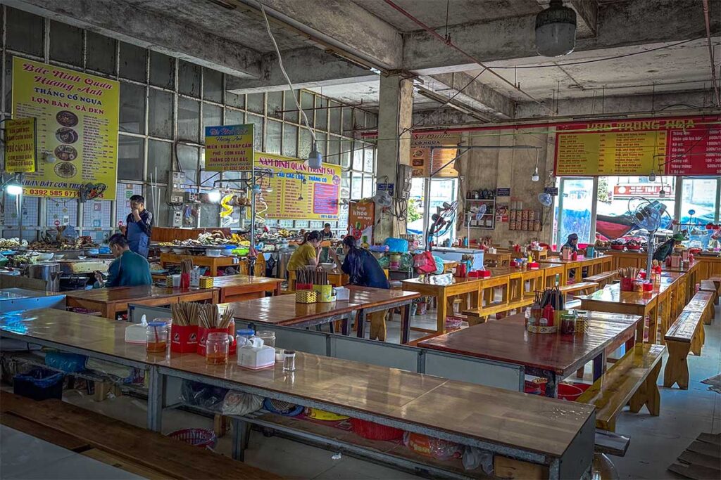 Small local food court with tables and benches inside the Central Market building of Sapa town
