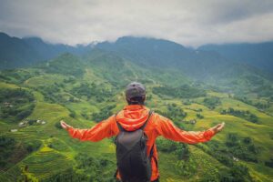 Trekker overlooking lush green rice terraces and mountains in Sapa during a guided trekking tour.