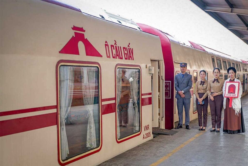 The Hanoi Five Gates double-decker tourist train at the platform, with staff in uniform welcoming passengers on this unique Vietnam train experience