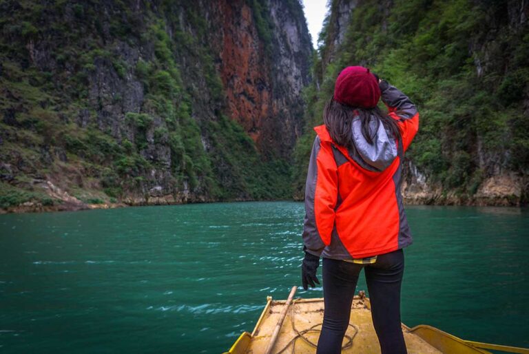 A woman standing on the tip of the boat while passing Tu San Canyon on the Nho Que River in Ha Giang