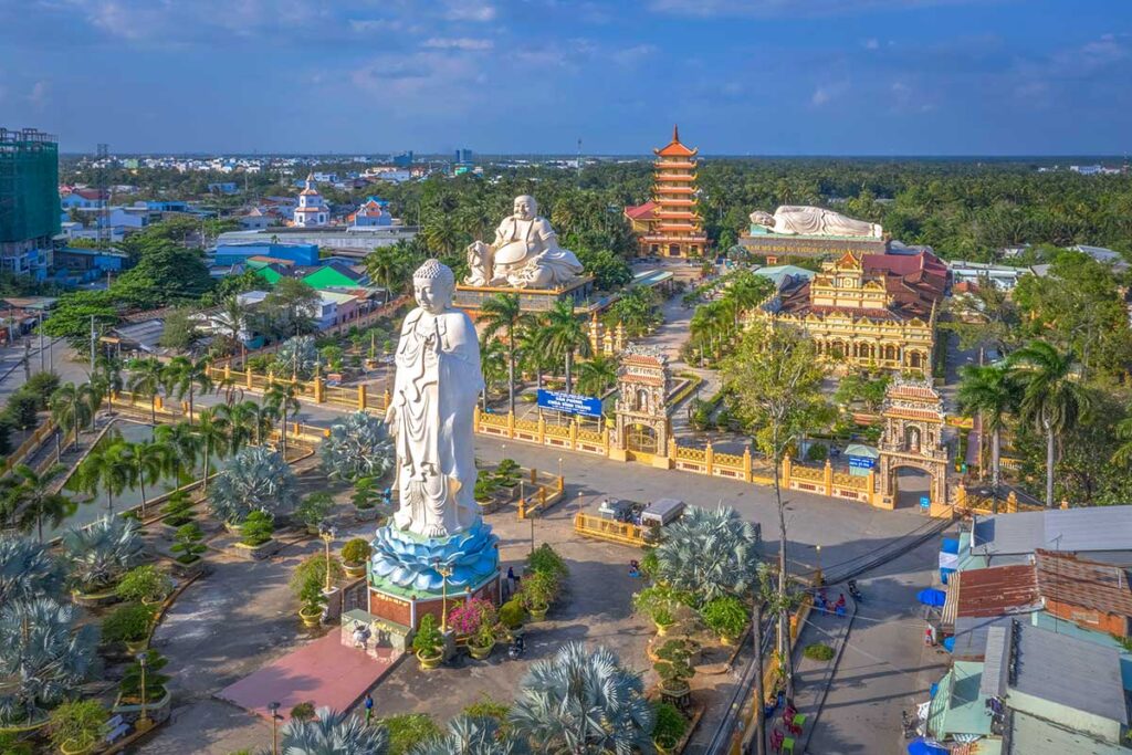 Aerial view of Vinh Trang Pagoda in My Tho, Tien Giang, featuring the giant standing Amitabha, seated Maitreya, reclining Shakyamuni Buddha, and seven-story tower.