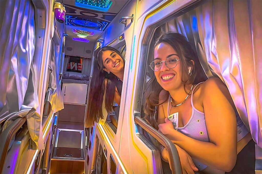 Two girls sticking their head out of the private cabin inside the VIP Limousine sleeper bus that drives from Hanoi to Sapa