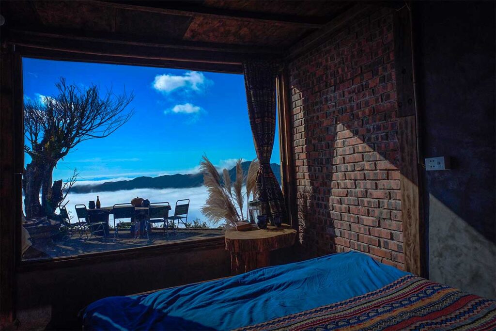 A bedroom in a local homestay in Ta Xua with a bed and window overlooking mountains and the clouds of Ta Xua - 1941M Homestay Ta Xua