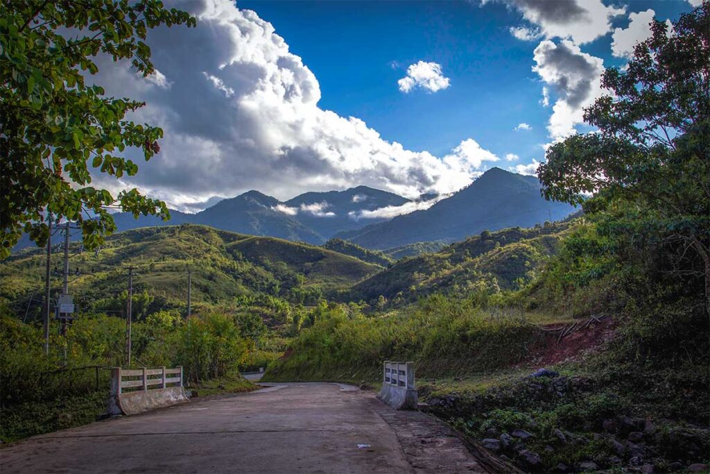 A scenic road in A Pa Chai that is surrounded by green forests and mountains