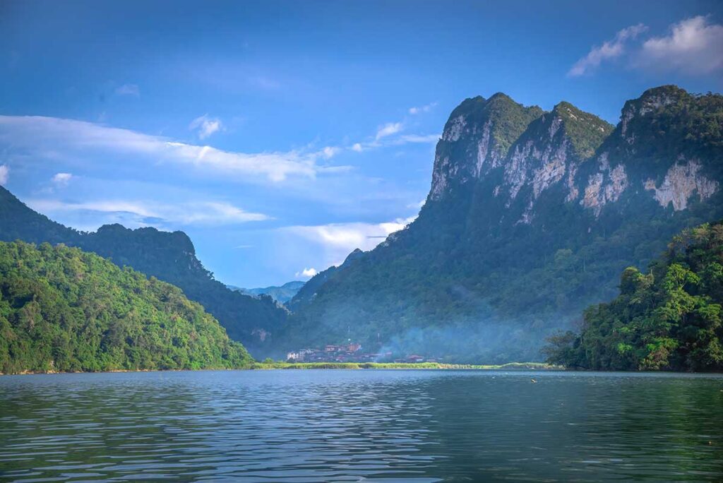 View over Ba Be Lake with far in distance a small village and a huge mountain behind that