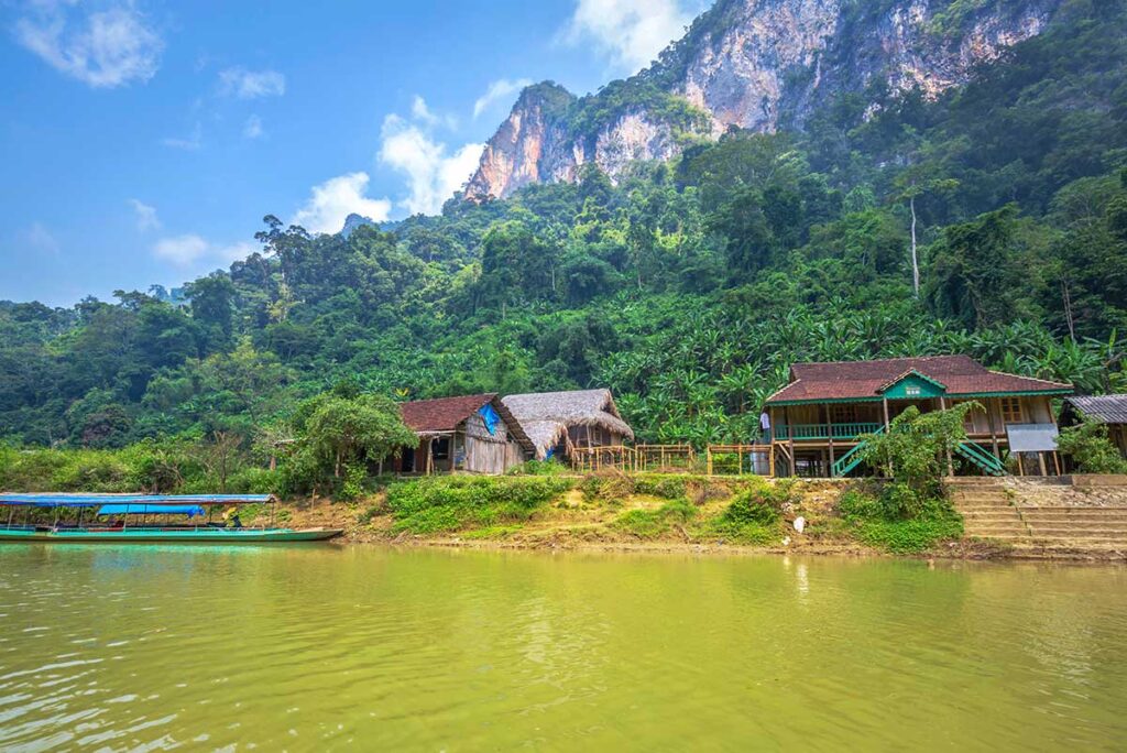A local village along Ba Be Lake with stilt houses and in the background forest and mountains of Ba Be National Park