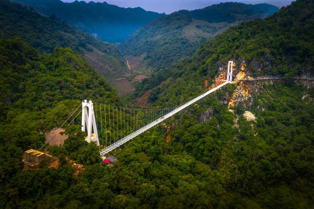 Aerial view of the long Bach Long Glass Bridge in Moc Chau, surrounded by mountains and jungle