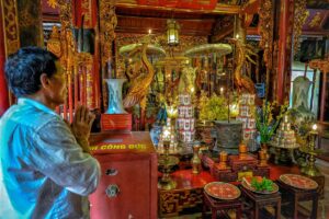A man praying at an altar with a white horse inside Bach Ma Temple in Hanoi