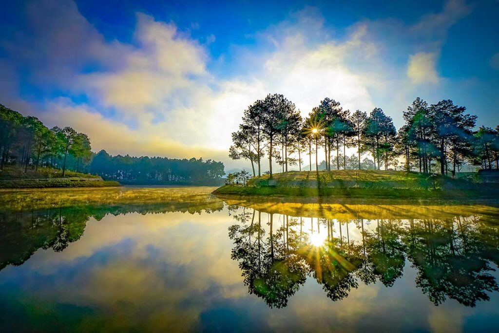 Sunbeams shining through trees and reflecting on the lake of Ban Ang Pine Forest