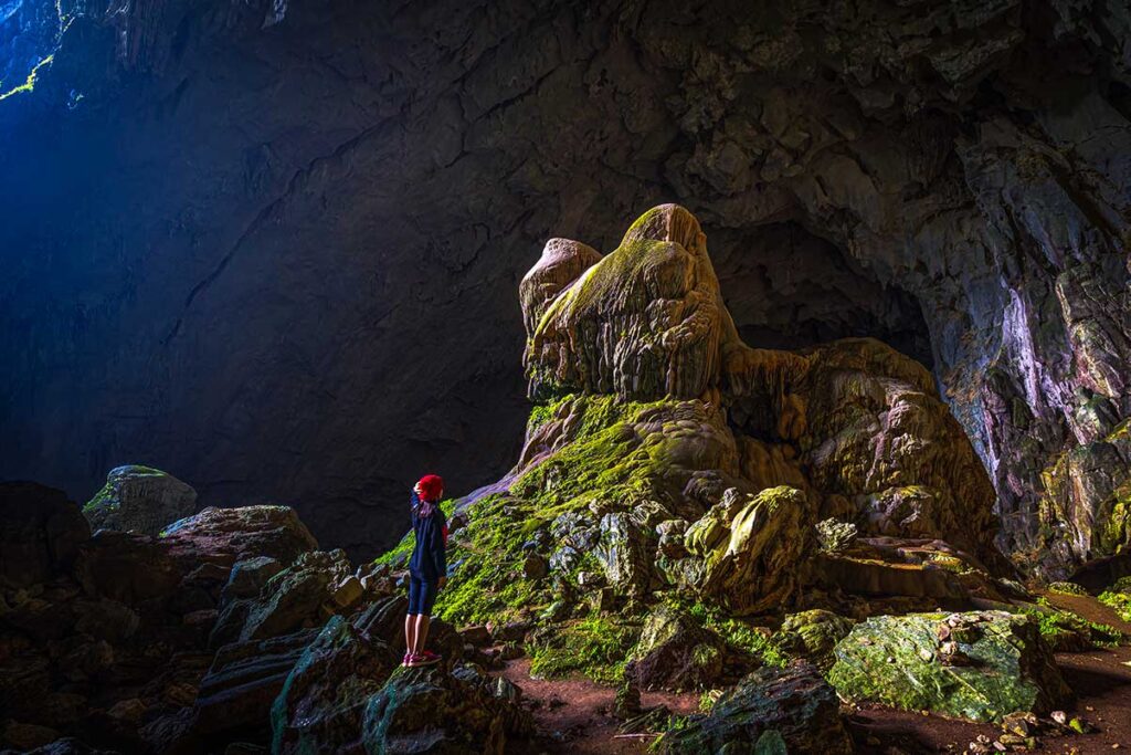 A traveller walking through the dark Bat Cave in Pu Luong