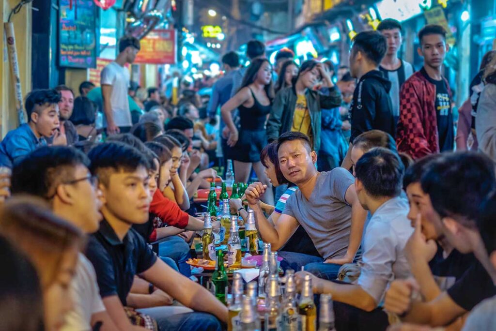 Lots of locals sitting around tables drinking beer at Bia Hoi Corner in Hanoi