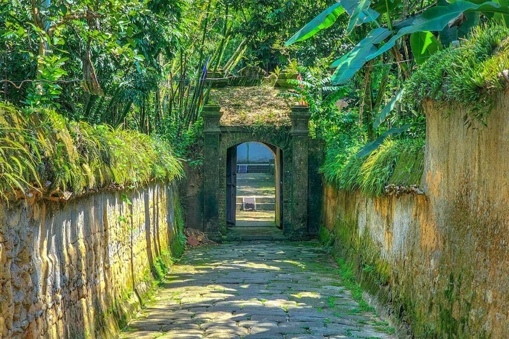 Moss covered walls and gate with trees overhanging at Bo Da Pagoda