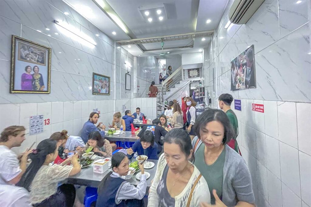 Locals and foreign travellers sitting at their tables inside Bun Cha Huong Lien - Obama Restaurant