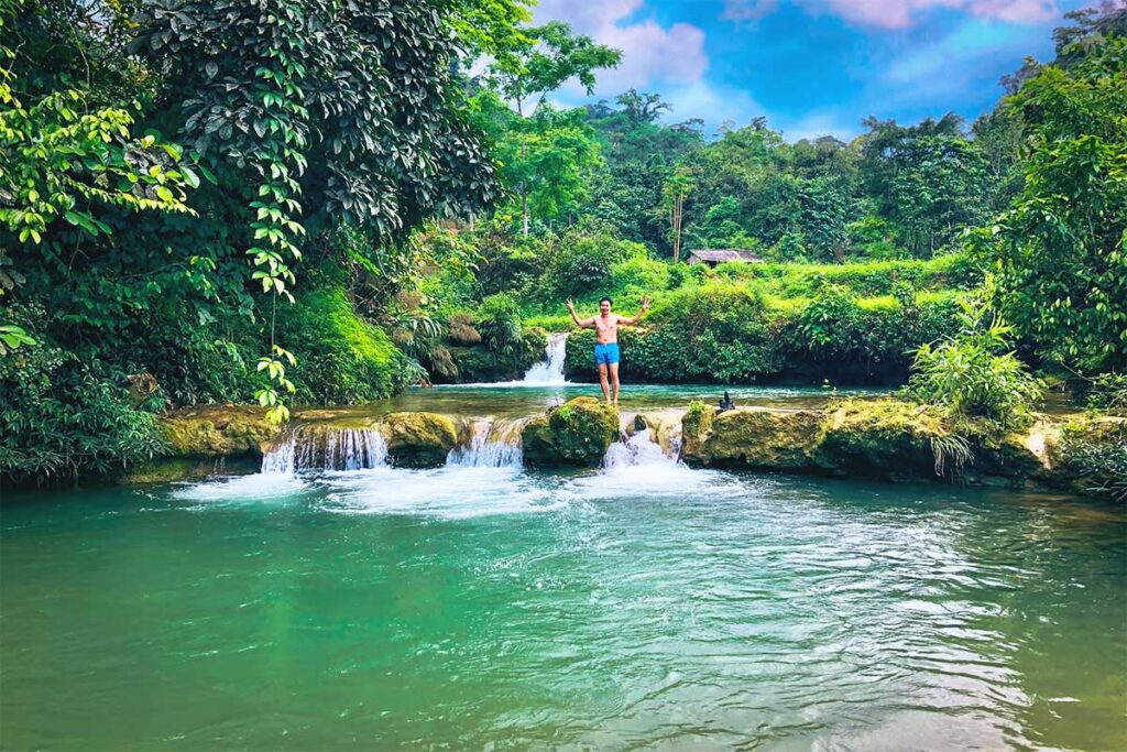 A man ready to jump from a very small waterfall in a beautiful stream near Buot Village