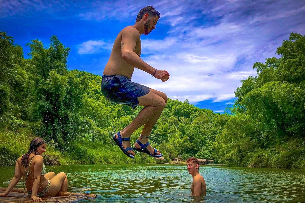 People jumping from a bamboo raft in a river in Pu Luong