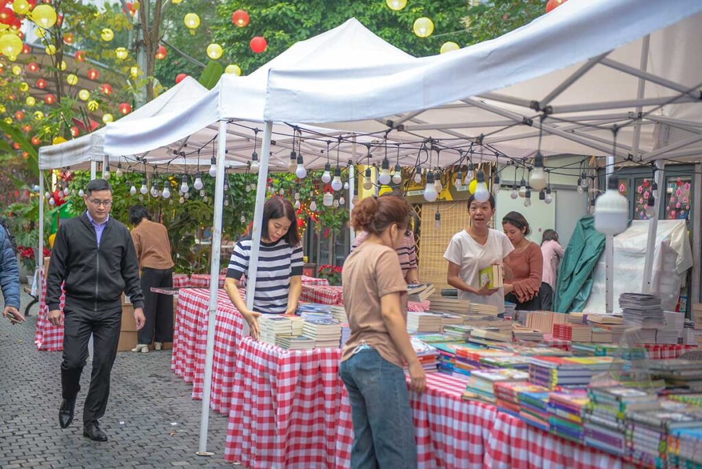 A woman browsing books at small pop-up street stalls at Hanoi Book Street