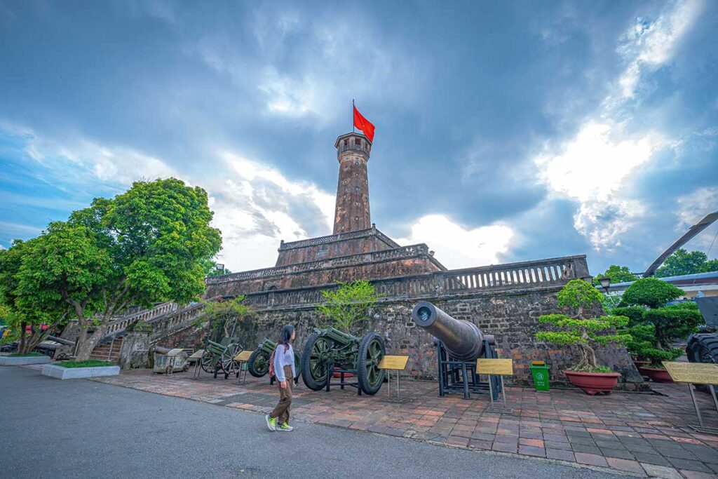A tourists walking by the canons of the Hanoi Flag Tower 
