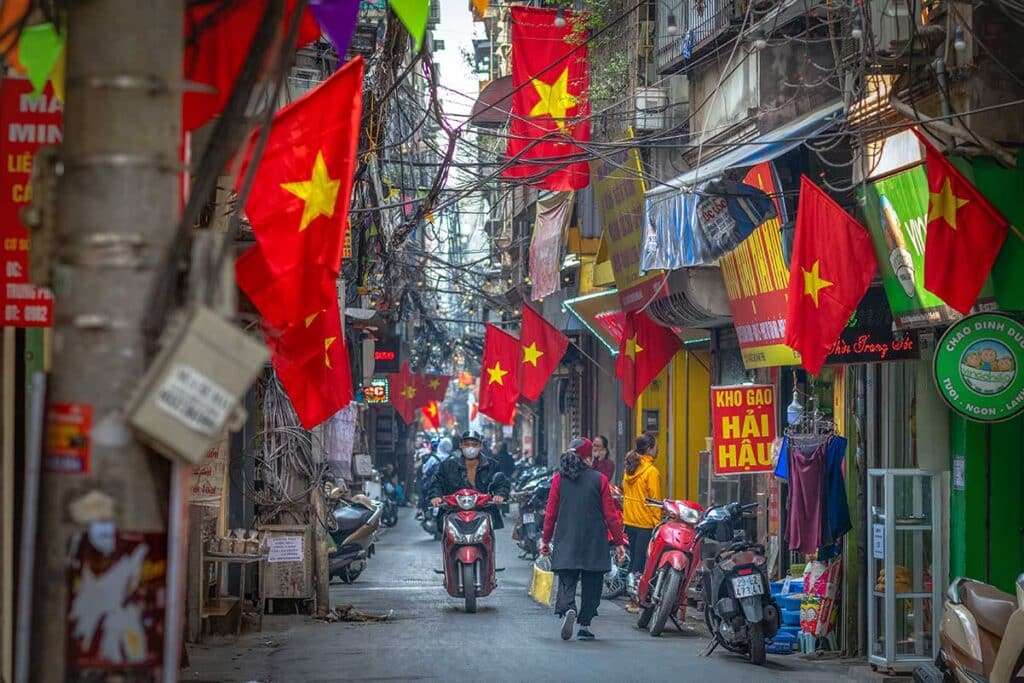 Many Vietnamese flags hanging in a narrow street within Hanoi Old Quarter