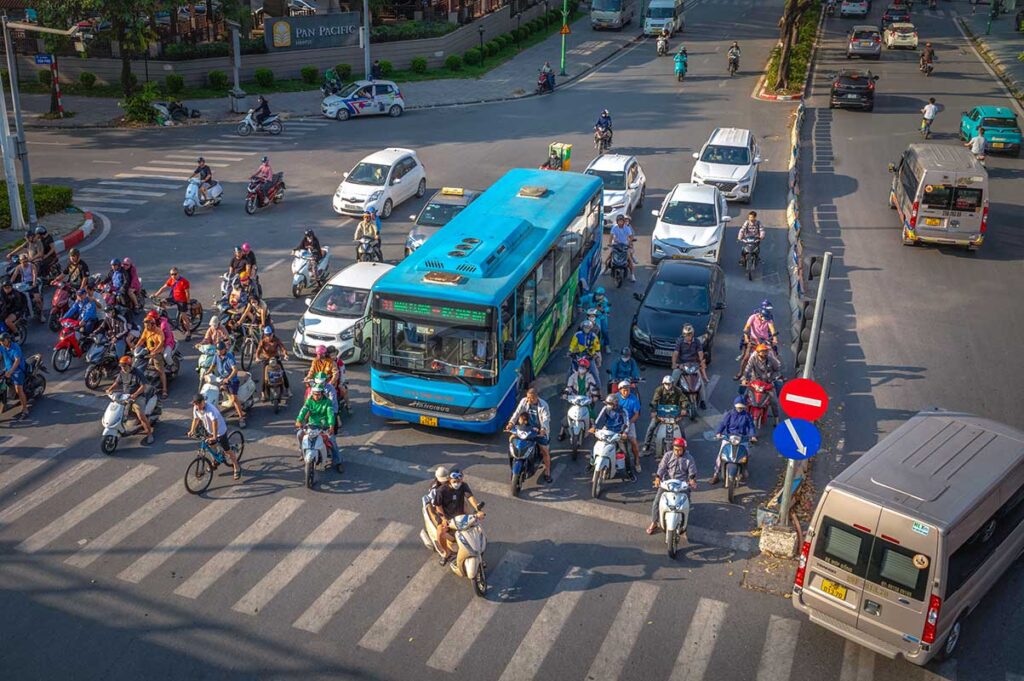 Chaotic Hanoi traffic with buses, motorbikes, cars and vans waiting at a traffic light