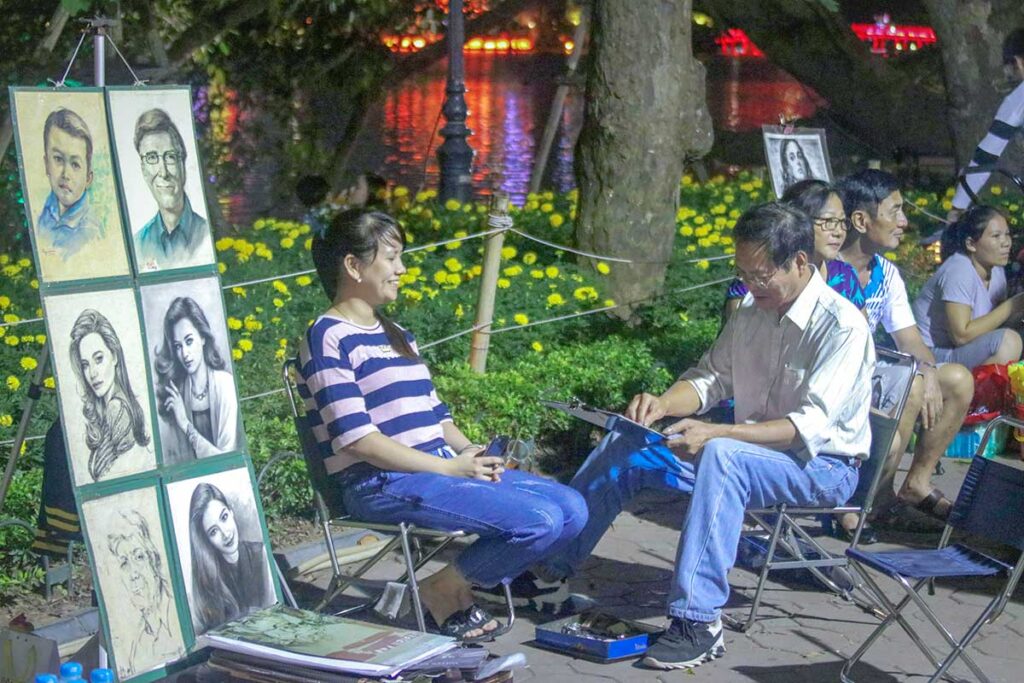 A local artist is making drawings of people at the Hanoi Weekend Night Market