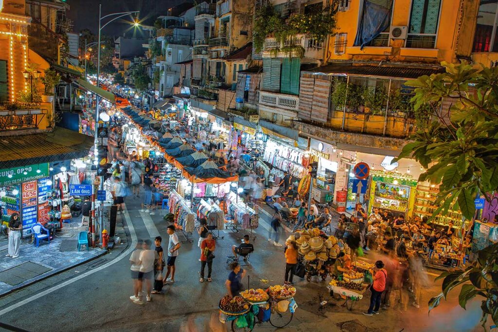 View over Hanoi Weekend Night Market with lots of people walking along the stalls seen from second floor building across the street
