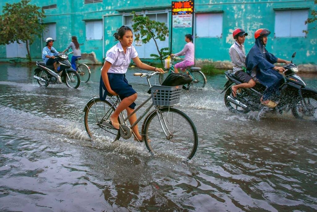 A girl cycling through the flooded streets of Ho Chi Minh City