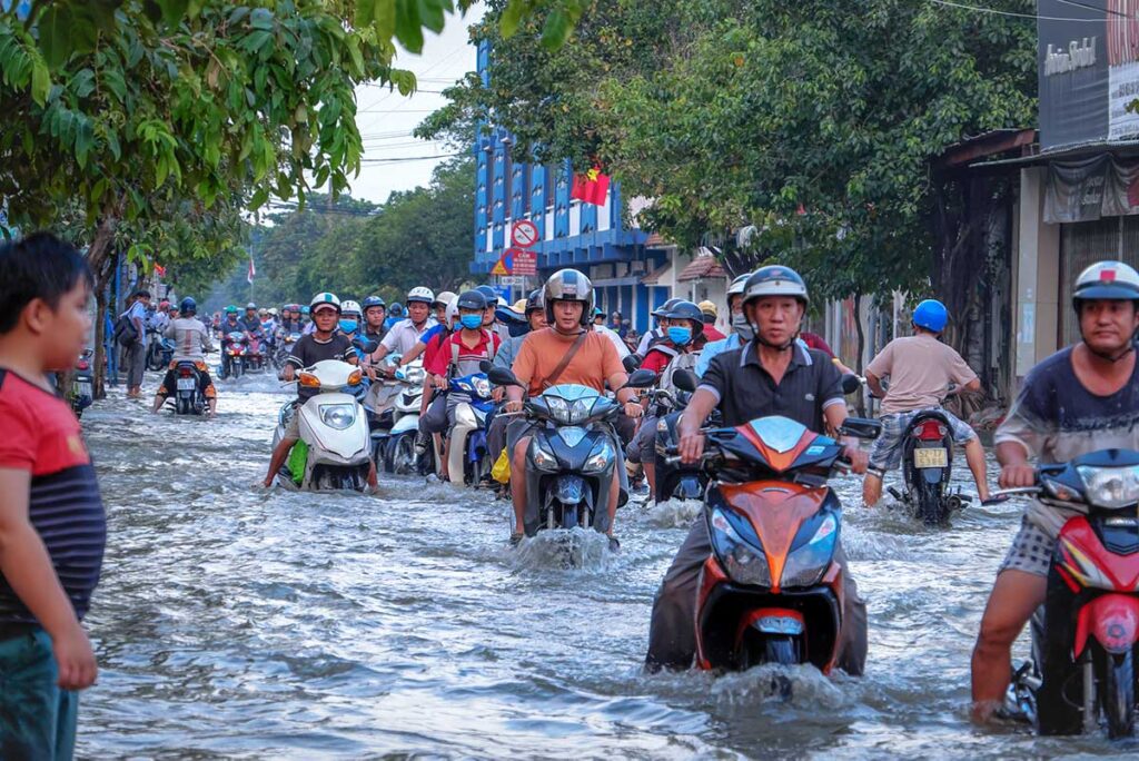Motorbikes in Ho Chi Minh City driving through the flooded streets during flooding in Vietnam