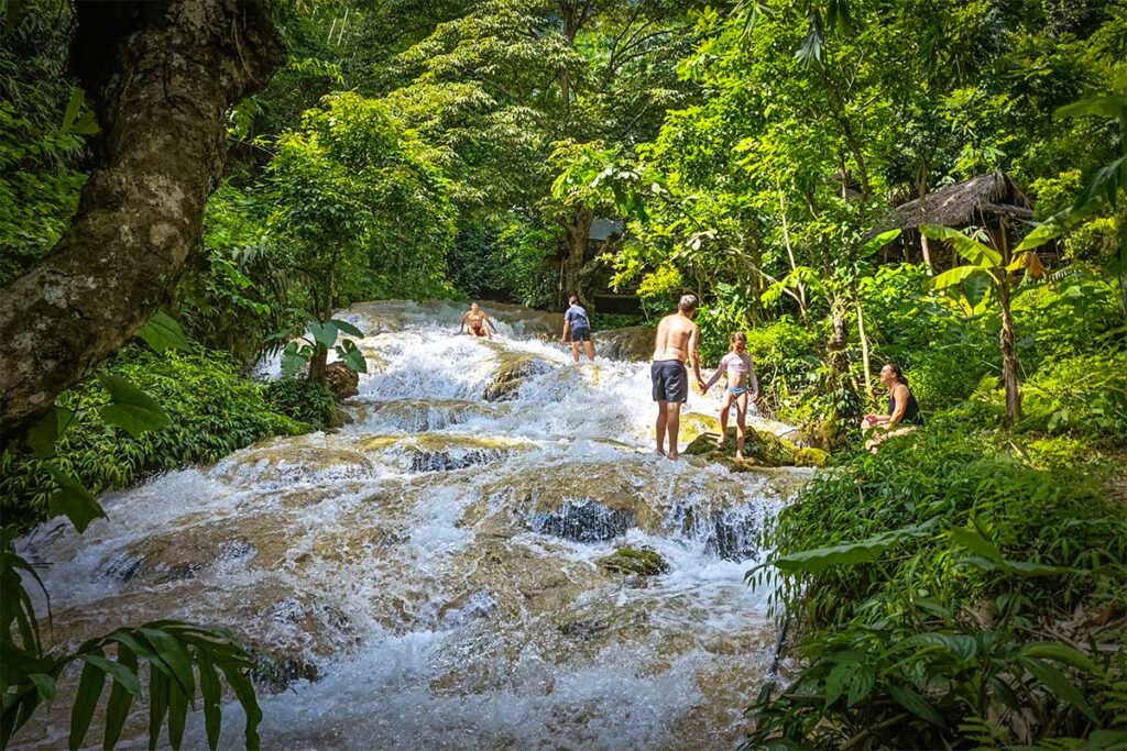 Tourist walking over the rocks in swimming wear at Hieu Waterfall