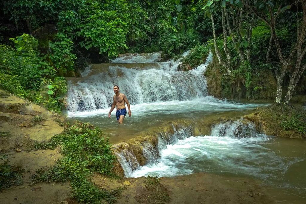 A foreign tourist in swimming short bathing in Hieu Waterfall