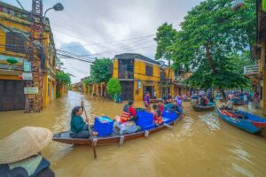 Local people using a boat through the ancient town of Hoi An during flooding in Vietnam