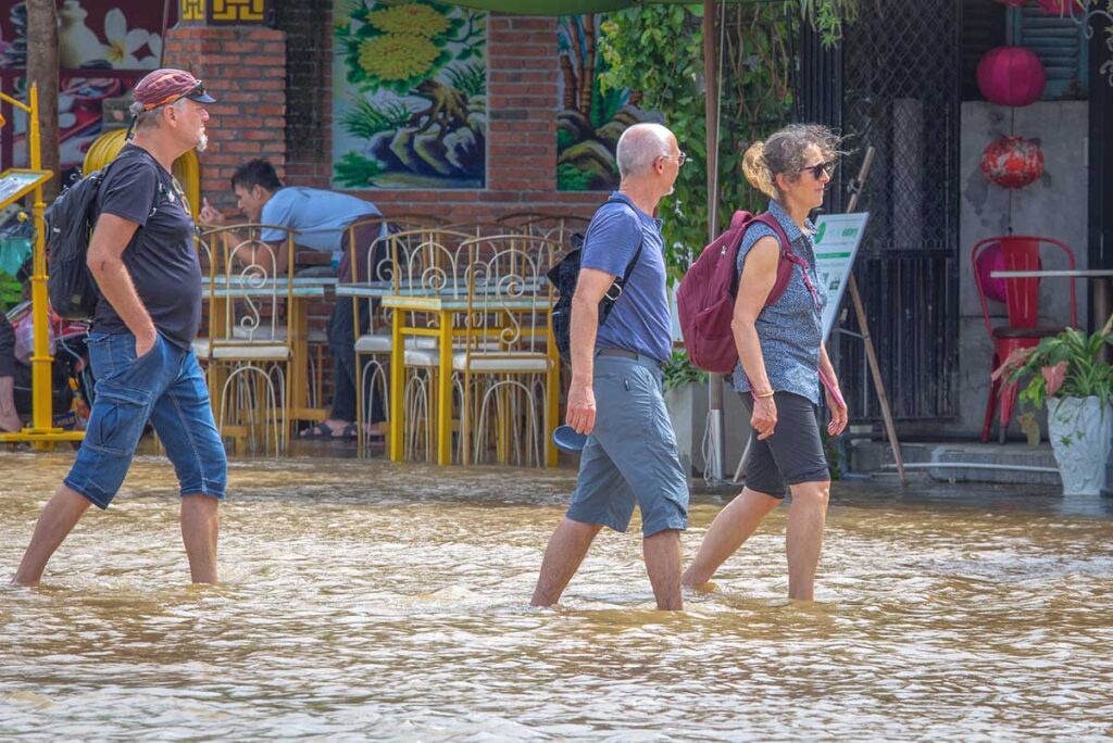 Tourists walking through ankle deep flooding streets of Hoi An