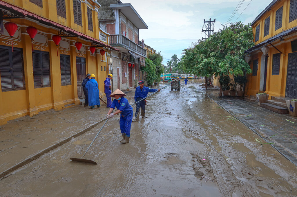 Locals cleaning the street from mud after flooding in Hoi An