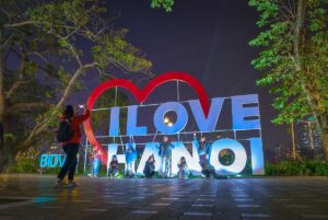 People are taking a photo in the evening at a NEON sign of "I love Hanoi" - Hanoi meaning
