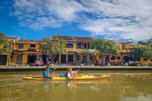 Kayaking along Hoi An’s riverfront with historic yellow houses lining the Thu Bon River