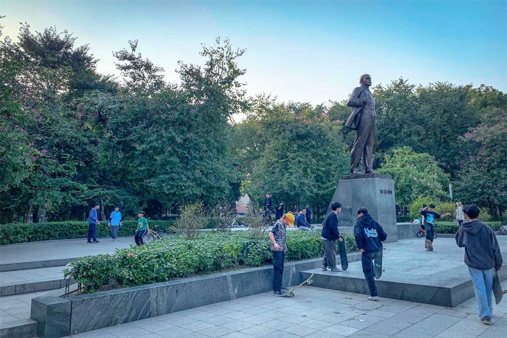 Kids playing with skateboards right next to the Statue of Lenin in Lenin Park in Hanoi