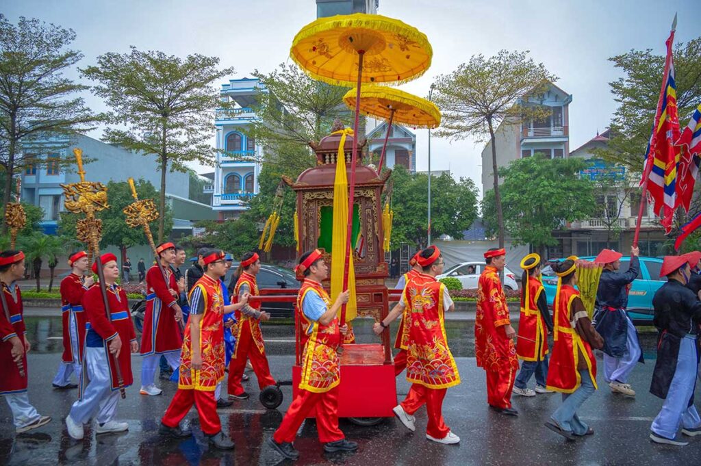 Colorful dressed people are in a parade and carrying an latar through the streets of Bac Ninh during the Lim Festival