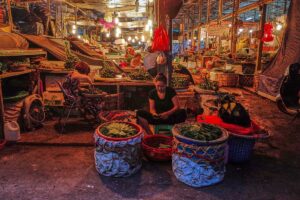 Local woman at night at the Long Bien Market selling fruit and vegtables