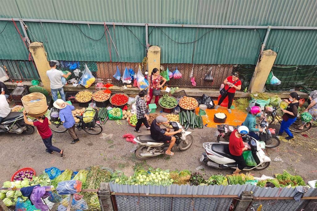 Locals on motorbikes driving along the Long Bien Market